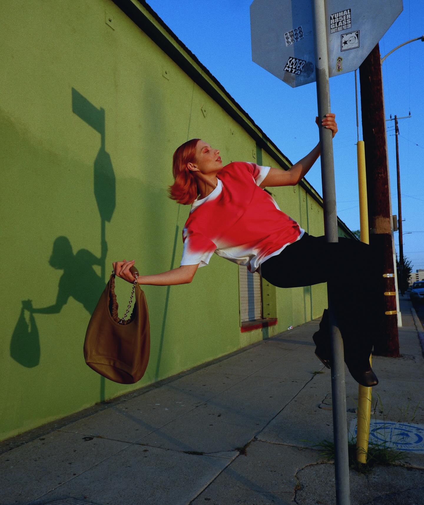 Creator posing playfully against a colorful mural while showcasing the LOEWE Squeeze bag in a social-first fashion shoot.