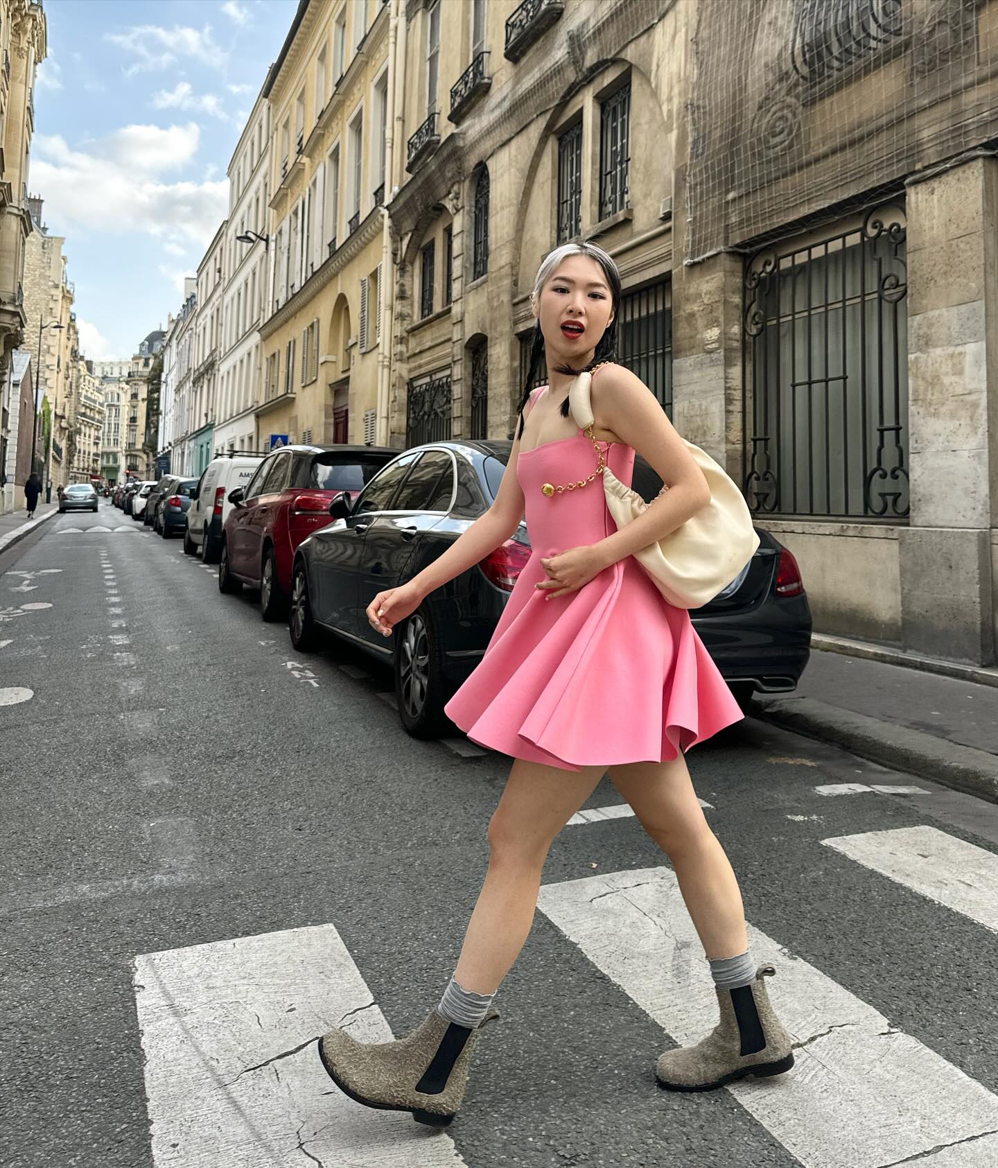 Creator walking across a Paris street in a pink dress carrying the LOEWE Squeeze bag as part of the luxury fashion campaign